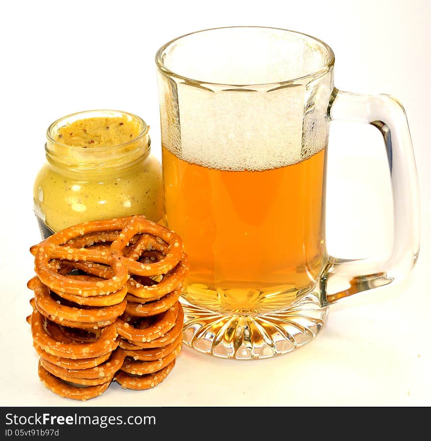 A stack of pretzels with a jar of mustard and a glass of beer. A stack of pretzels with a jar of mustard and a glass of beer.