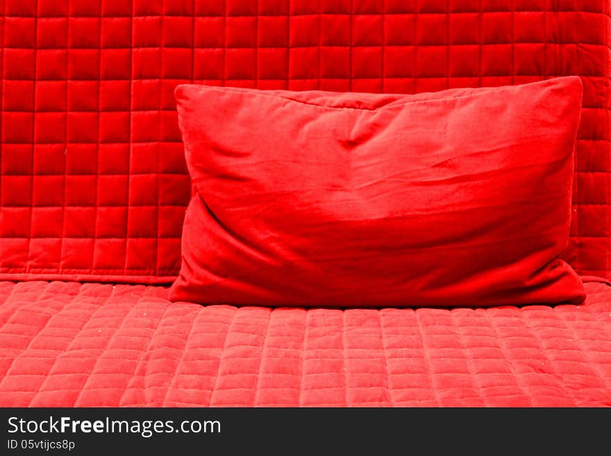 Red pillow on red textured blanket