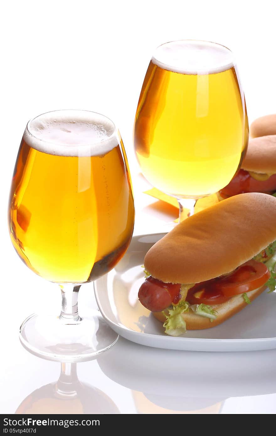 Hot dog with a glass of lager beer on a white background. Hot dog with a glass of lager beer on a white background