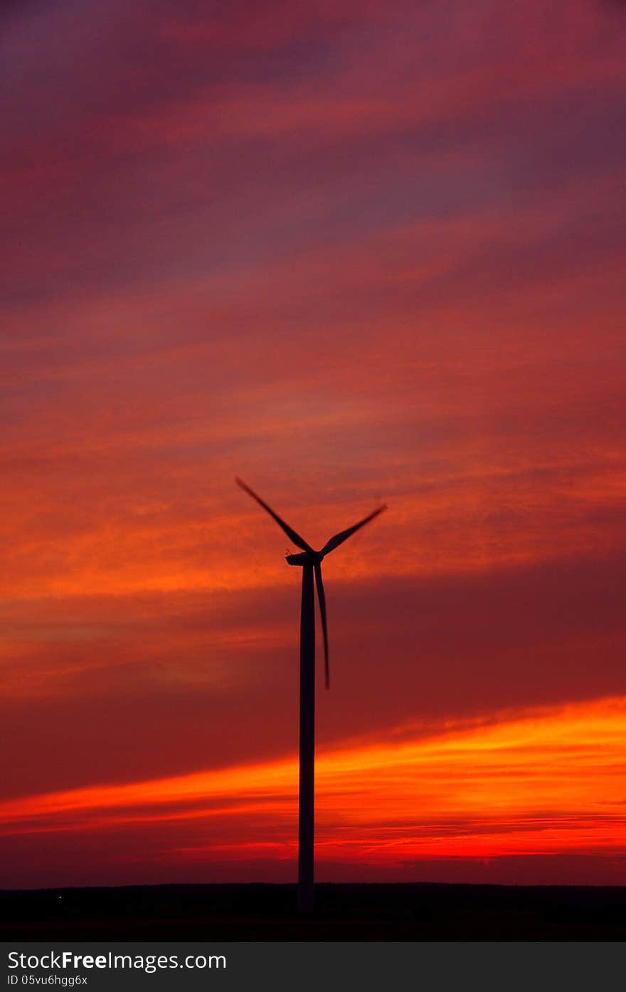 The photograph shows wind turbines on the background of the evening sky. The photograph shows wind turbines on the background of the evening sky.