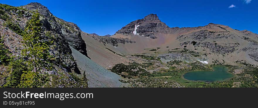 This image of the rugged mountains with some remaining snow fields and the mountain lake was taken in Glacier National Park, Montana. This image of the rugged mountains with some remaining snow fields and the mountain lake was taken in Glacier National Park, Montana.