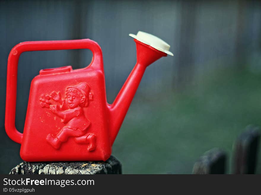 Watering can on the fence of the playground. Watering can on the fence of the playground