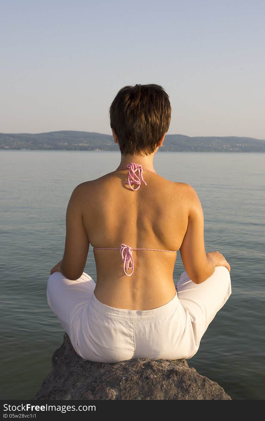 A young girl meditating on the lakeside. A young girl meditating on the lakeside.