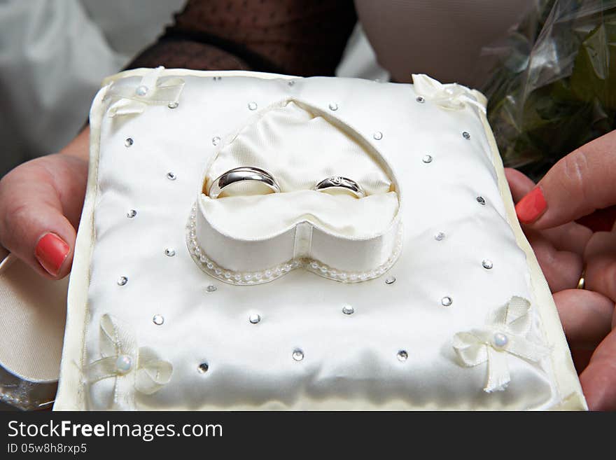 Gold wedding rings on white pillow