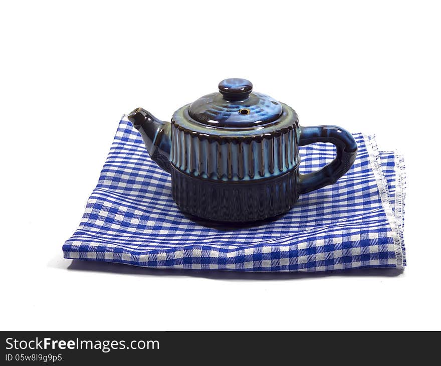 Ceramic blue teapot on the napkin isolated on the white background. Ceramic blue teapot on the napkin isolated on the white background