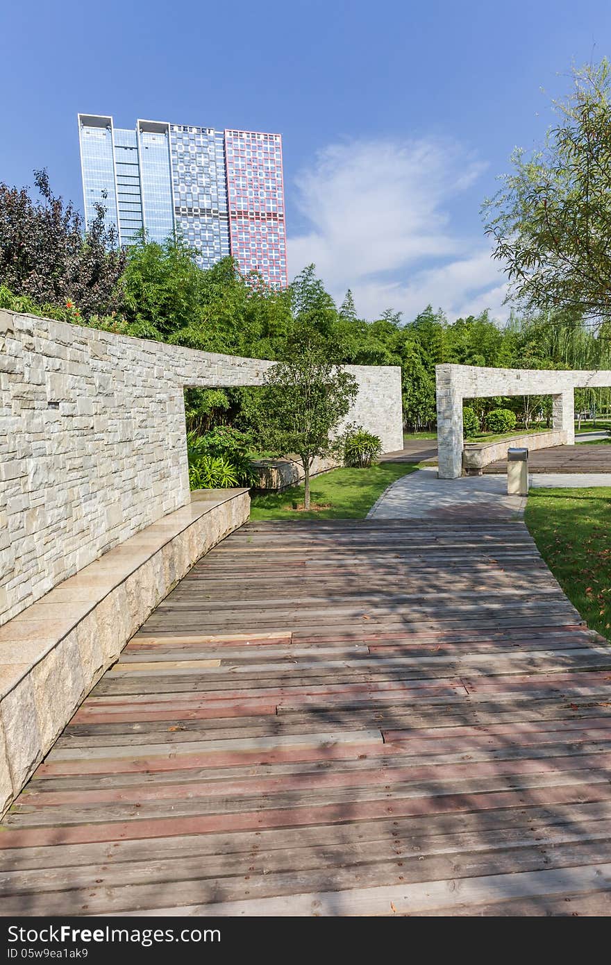 Cultural stone wall with wooden walkway in a city garden. Cultural stone wall with wooden walkway in a city garden