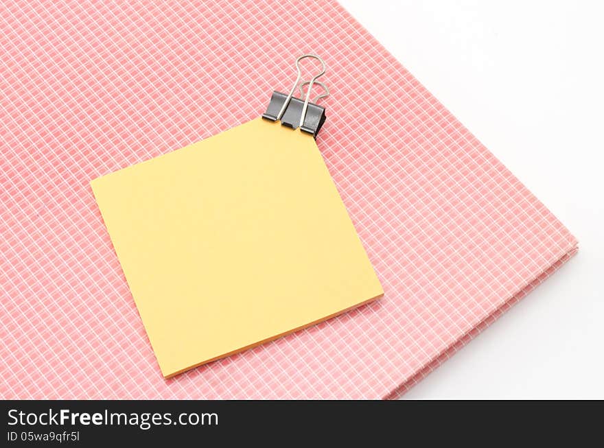 Red notebook with post it and bulldog clip isolated on white