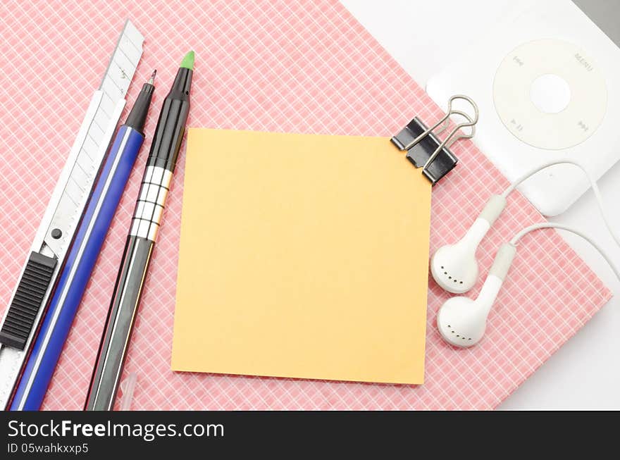 Red notebook with post it and bulldog clip blue pen cutter ear phone isolated on white background