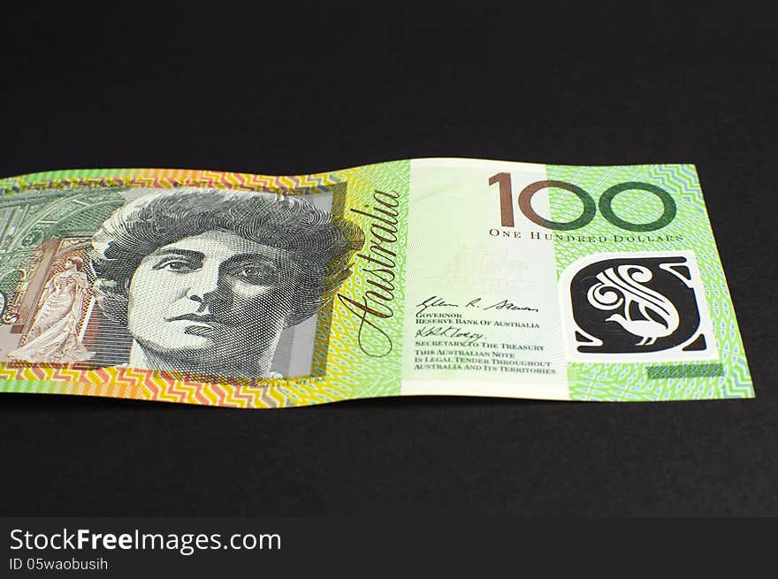 Australian green and gold 100 hundred dollar note, against a black background. Australian green and gold 100 hundred dollar note, against a black background.