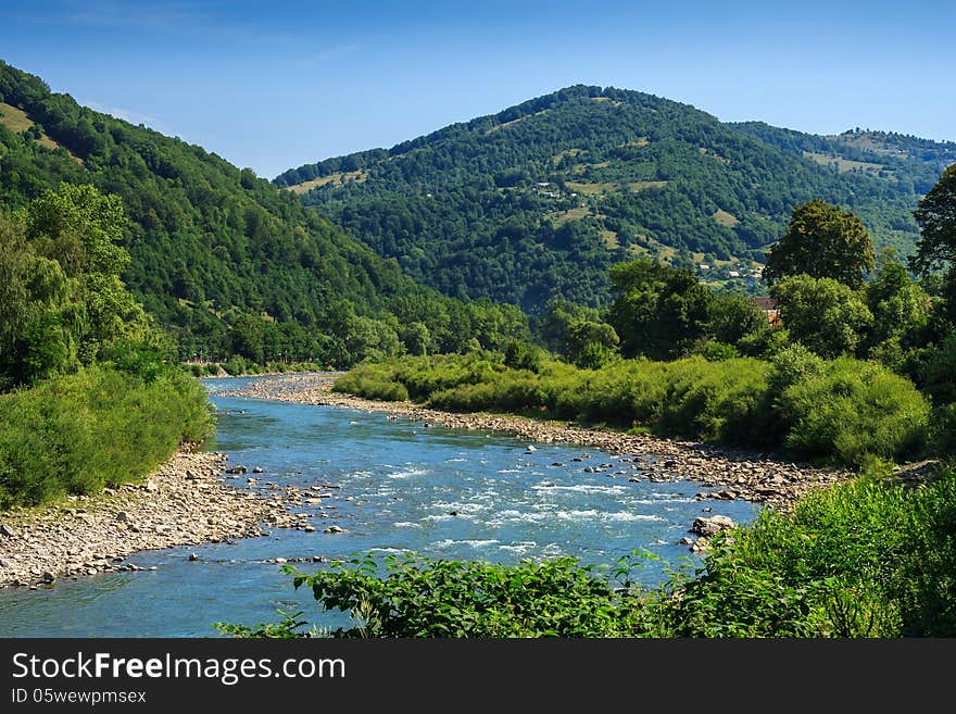 River meanders through the village at the foot of the mountains. River meanders through the village at the foot of the mountains