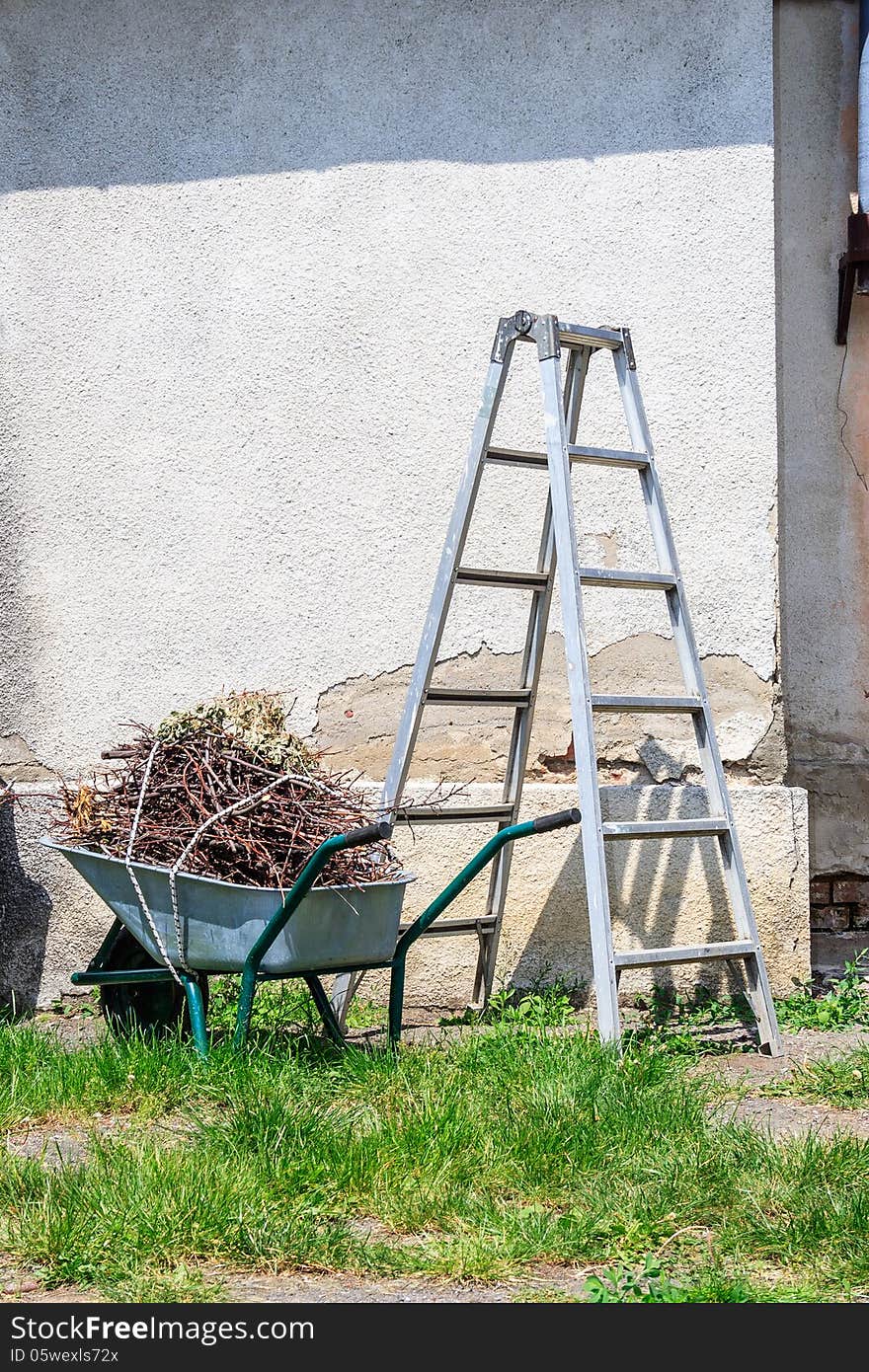 Metal Ladder And A Wheelbarrow By The Old Wall