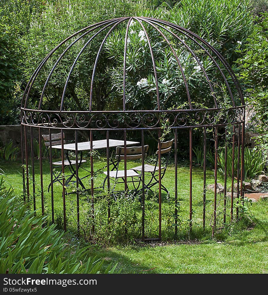 Romantic open garden house with table and chairs surrounded by flowers. Romantic open garden house with table and chairs surrounded by flowers