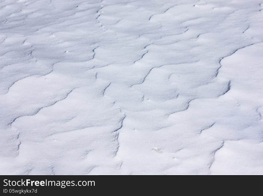 Wavy blue snow surface under bright sunlight, closeup view