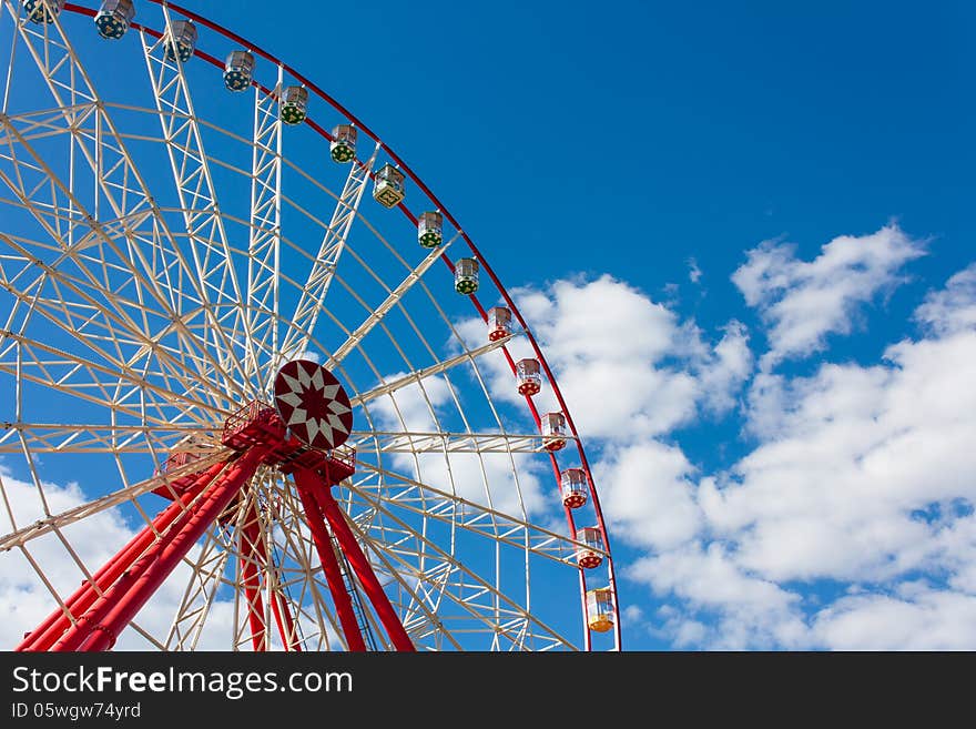 Ferris wheel in the summer in the blue cloudy sky. Ferris wheel in the summer in the blue cloudy sky