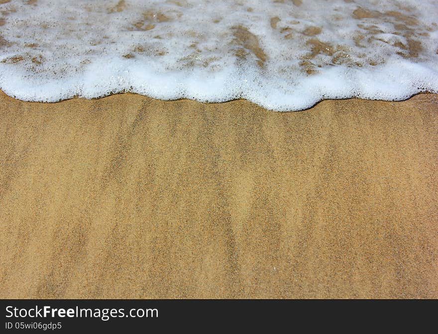 Sea ​​waves and wet sand on the beach as summer background