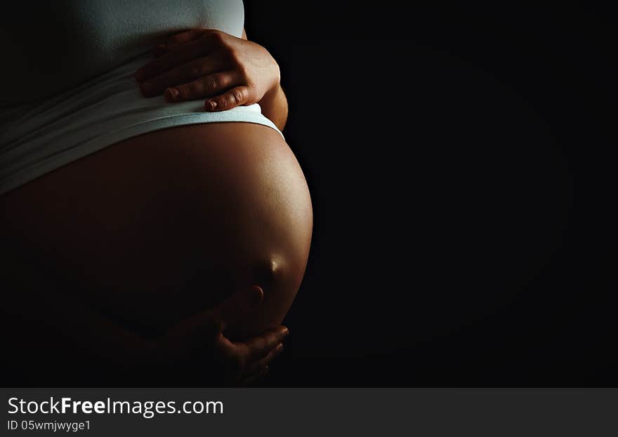 Belly of pregnant woman monochrome on a dark background