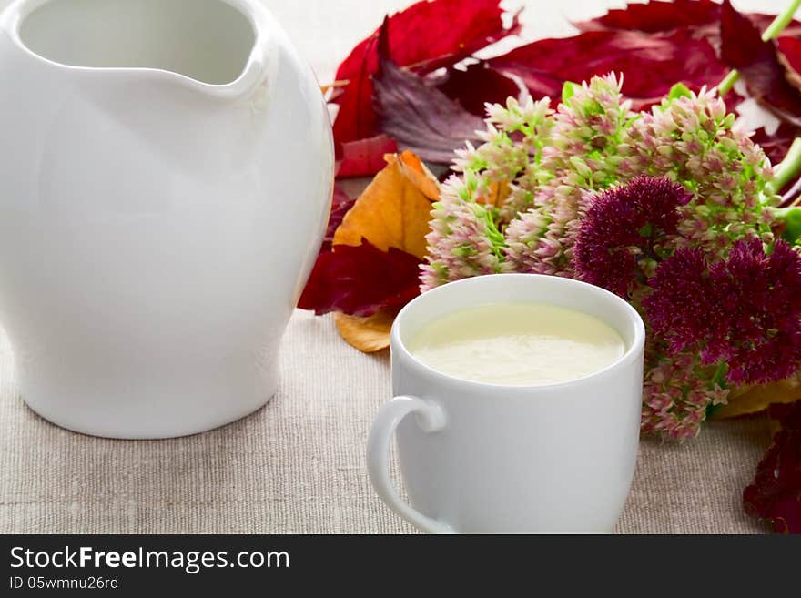 A cup of milk milk jug autumn leaves and flowers. A cup of milk milk jug autumn leaves and flowers