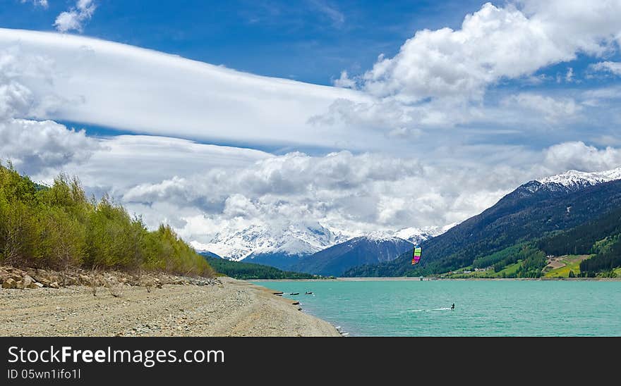 Kitesurfer on Reschen lake with Ortler mountains in background.