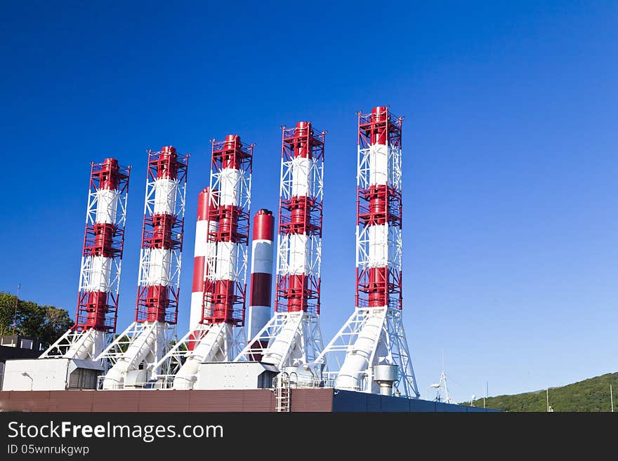 Power plant pipes against the blue sky in the bright sunny day