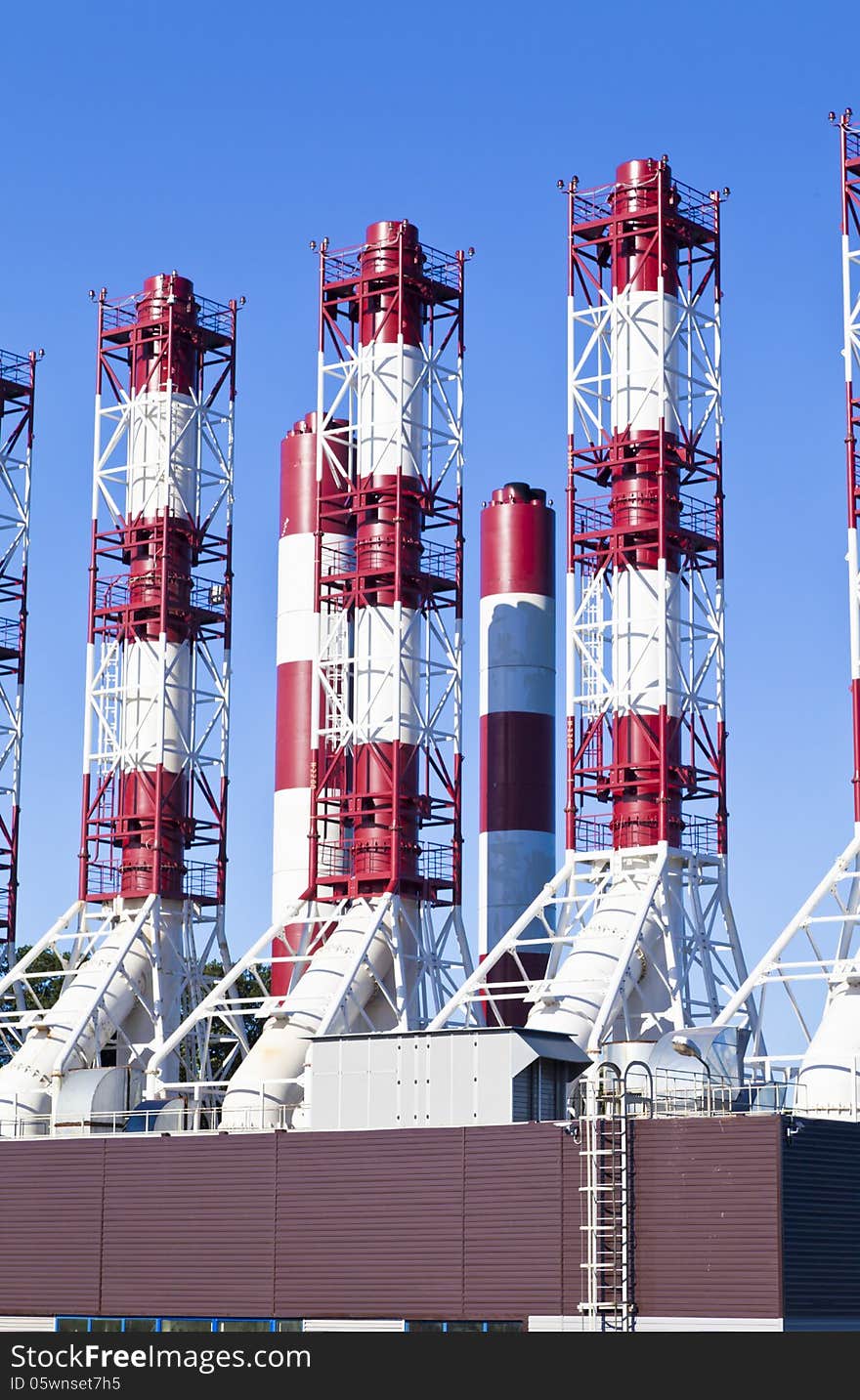 Power plant pipes against the blue sky in the bright sunny day