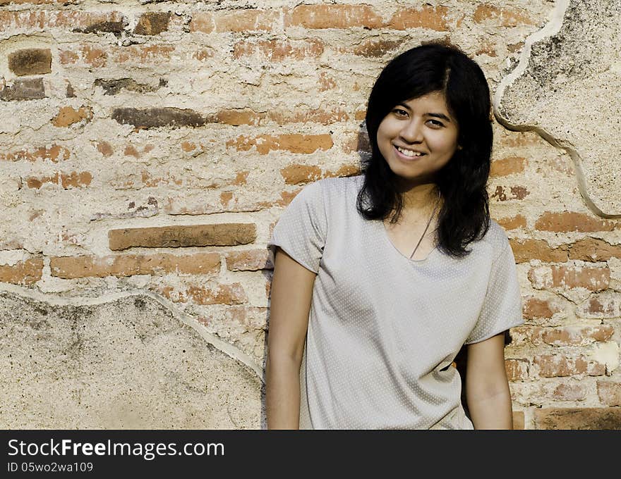 Pretty Girl Smiling While Standing Near Brick Wall