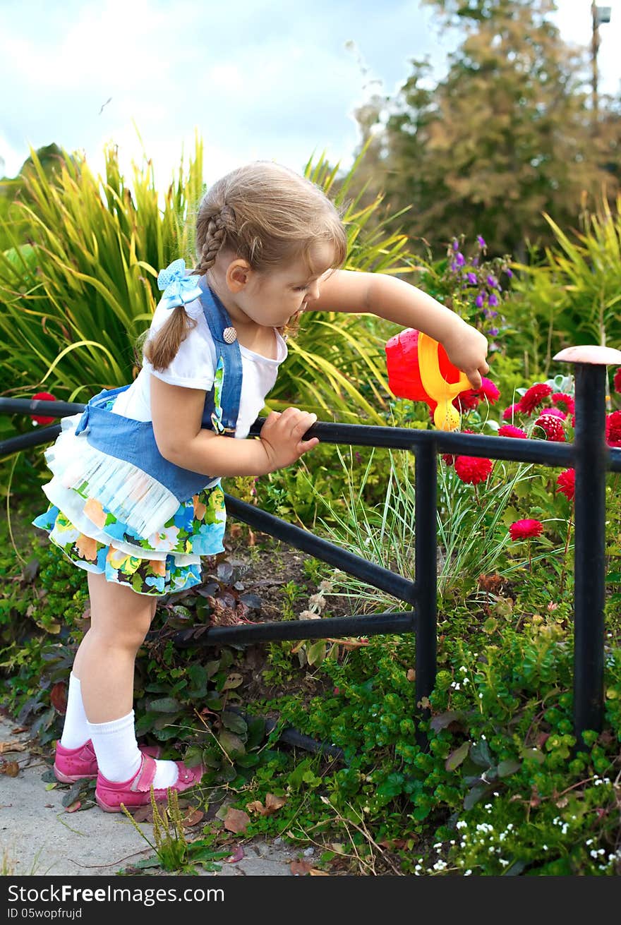 Portrait little girl watering the grass