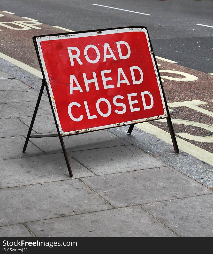 Grungy road closed sign on street stone pavement