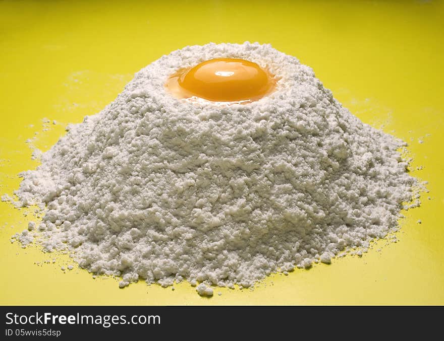 Wheat flour with egg on a yellow background. Wheat flour with egg on a yellow background