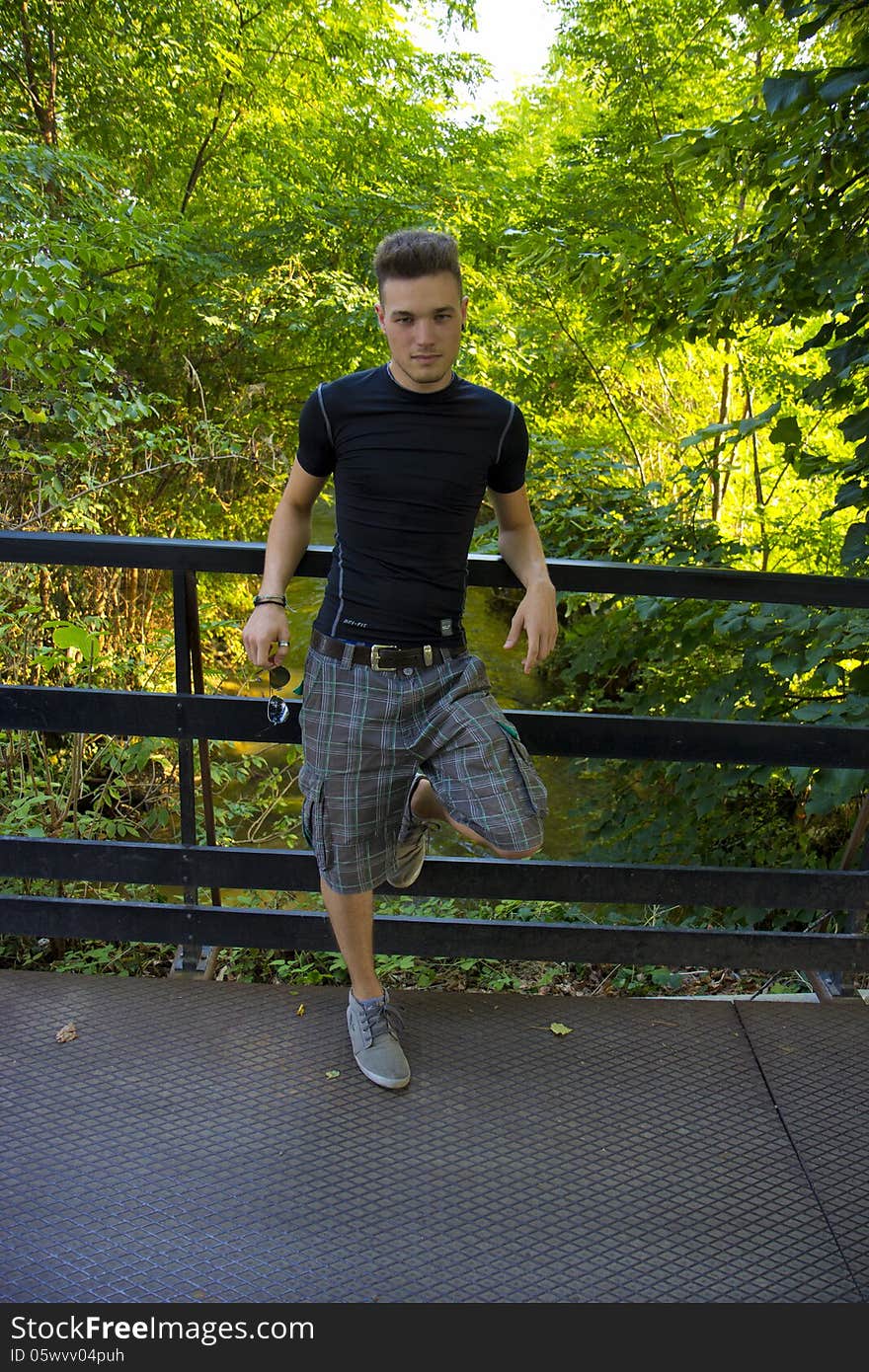 Handsome guy standing leaning on a fence. Handsome guy standing leaning on a fence