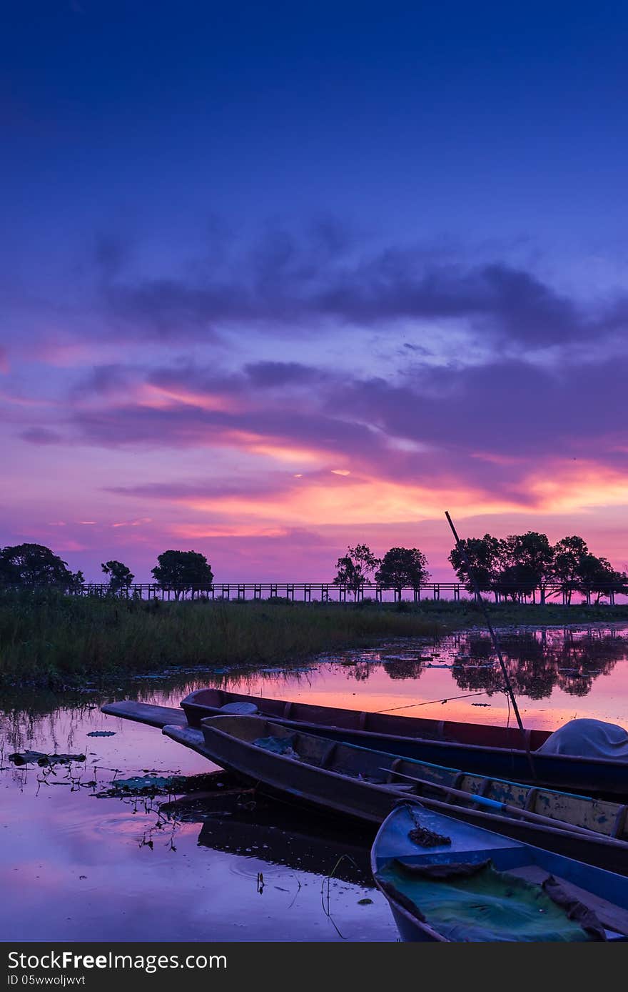 Docked boat on swamp field at dawn with beautiful vivid sky