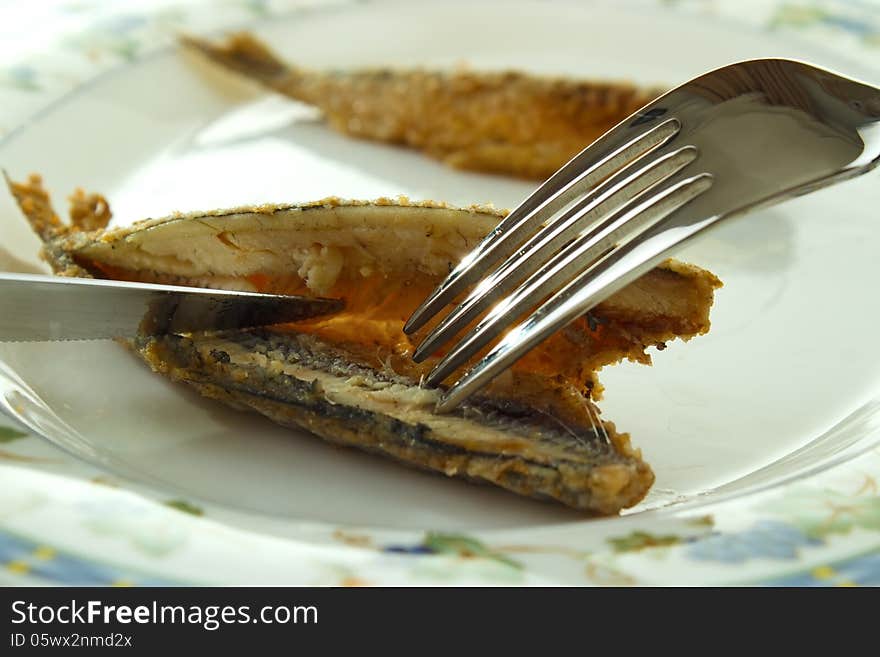 Cleaning cooked fish (fried vendace, small freshwater whitefish) for eating with fork and knife