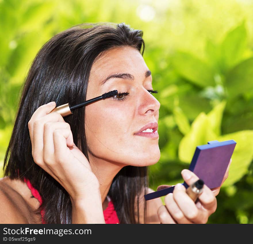 Beautiful woman making up over green background. Beautiful woman making up over green background.