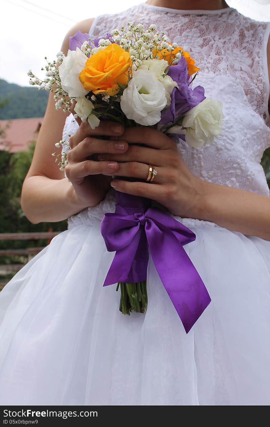 Bride holding near her body the wedding bridal bouquet.