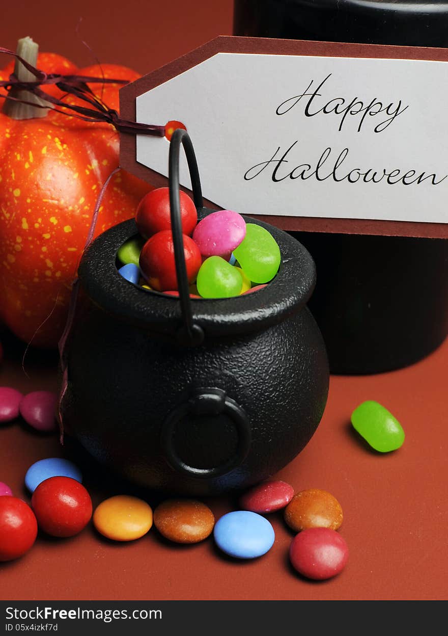 Row of Halloween Trick or Treat witches cauldrons full of candy on autumn brown background with black candle and orange pumpkin. Row of Halloween Trick or Treat witches cauldrons full of candy on autumn brown background with black candle and orange pumpkin.