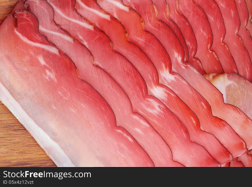 Slices of Delicious Smoked Pork In a Row closeup on Wooden Background. Slices of Delicious Smoked Pork In a Row closeup on Wooden Background