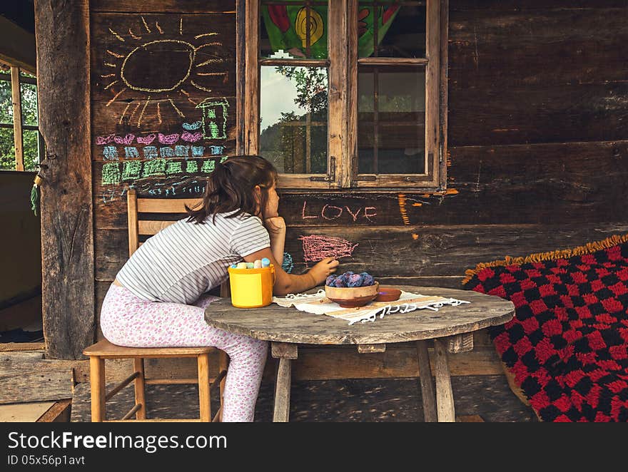 Child in front of a wooden house, playing and painting with chalk on wall. Child in front of a wooden house, playing and painting with chalk on wall.