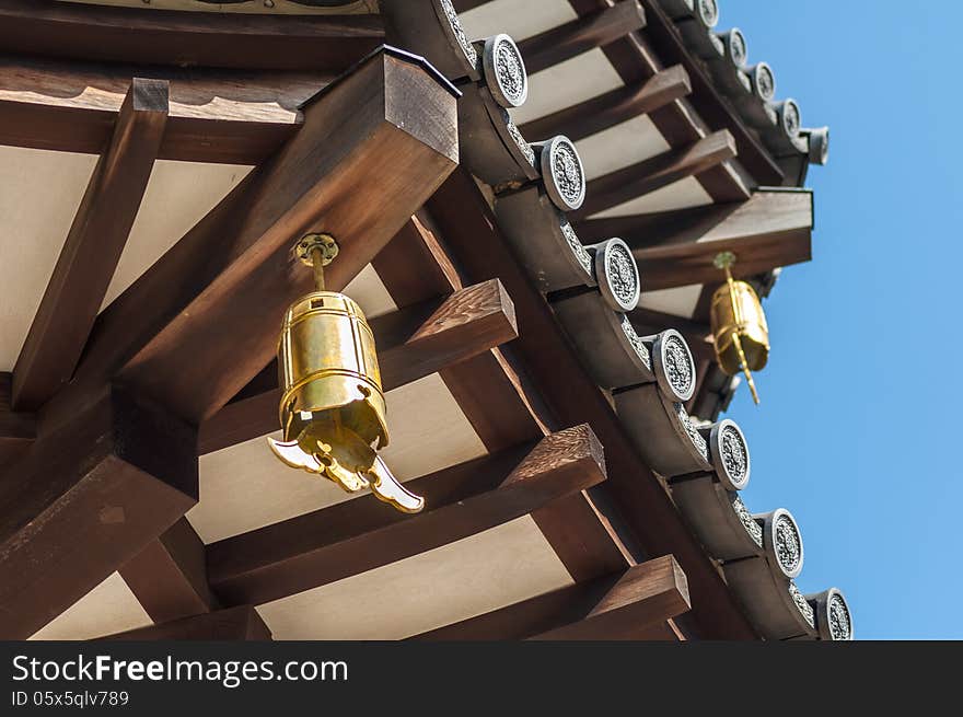 Close-Up view of underside of Japanese Pagoda Roof with Bells, Wooden Beams and Grey Tiles. Close-Up view of underside of Japanese Pagoda Roof with Bells, Wooden Beams and Grey Tiles