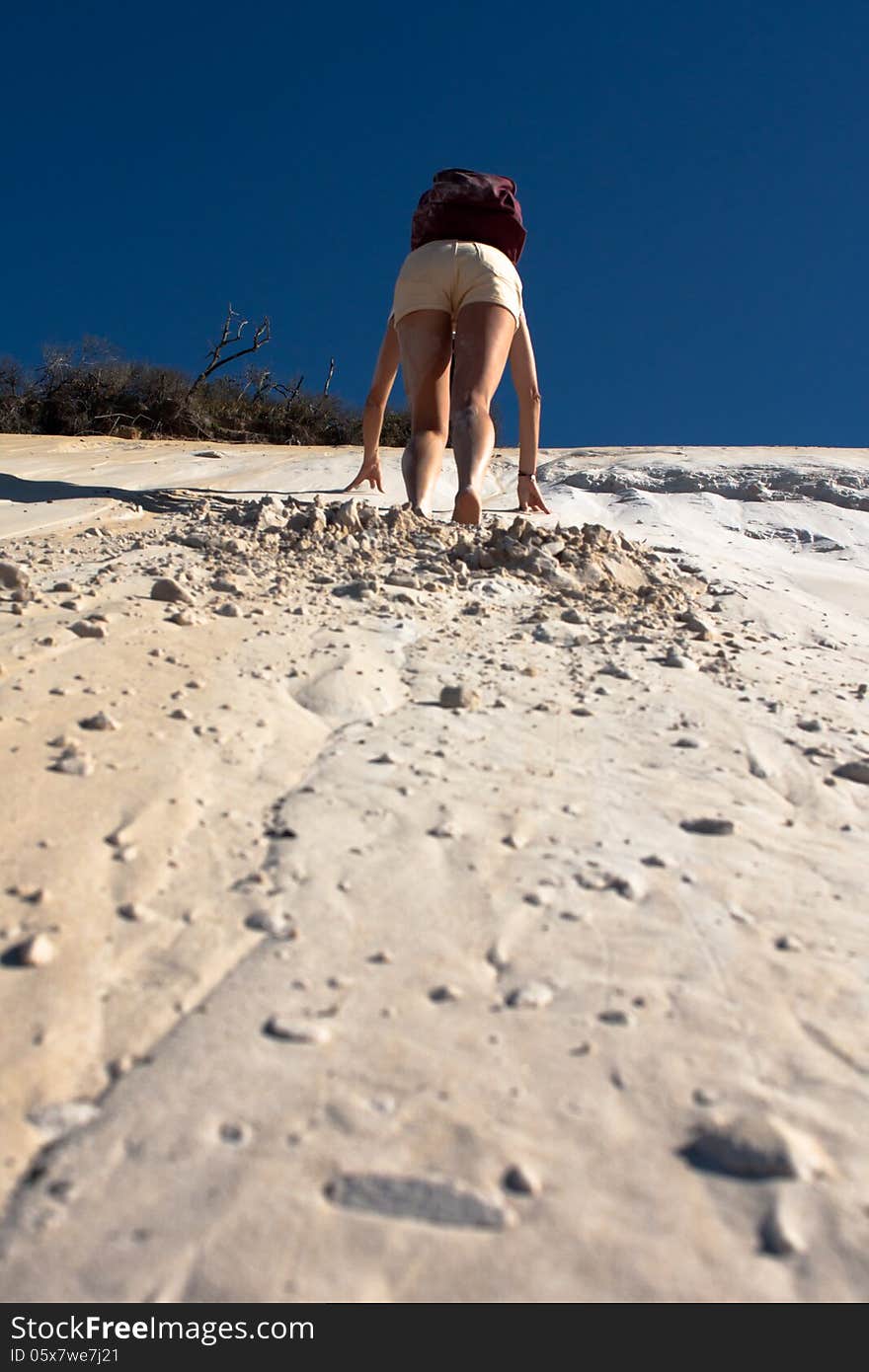 A woman climbs the dune in rainbow beach, queensland, australia. A woman climbs the dune in rainbow beach, queensland, australia