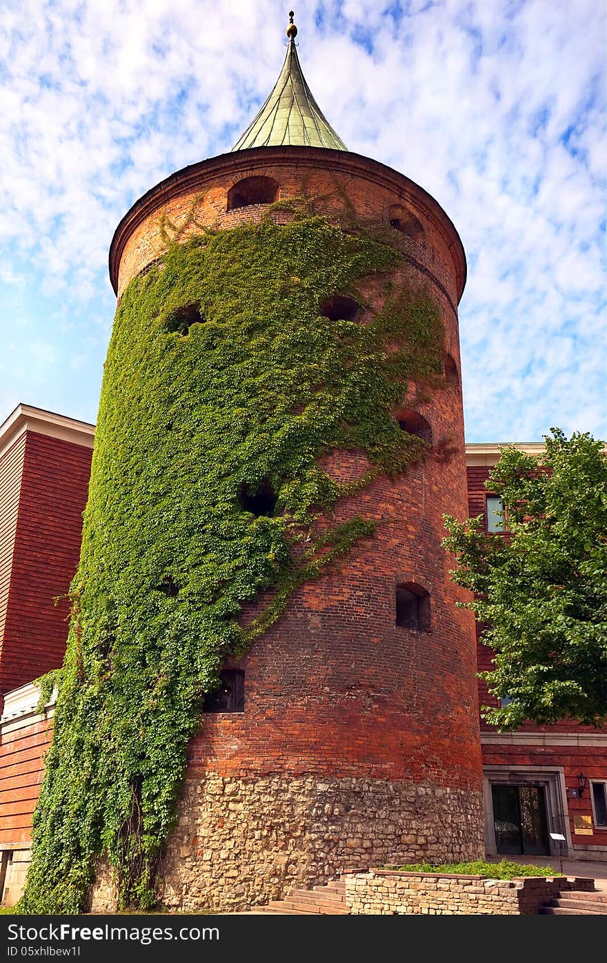 Antique powder tower of red brick green entwined with ivy