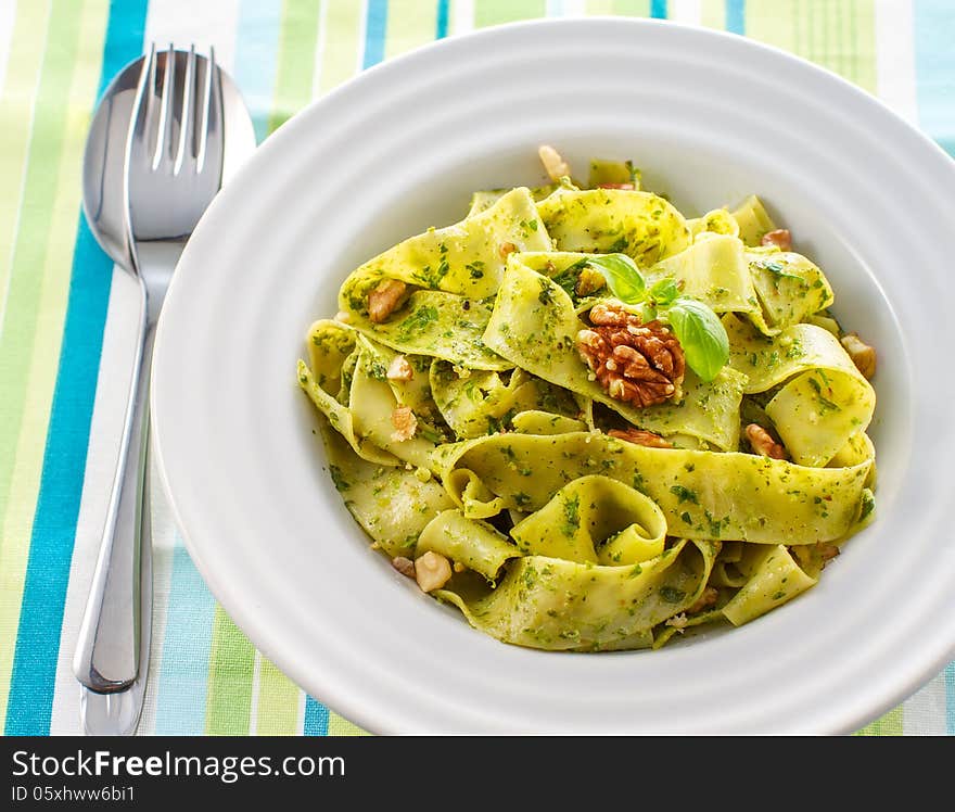 Tagliatelle pasta with pesto and walnuts on white plate. Tagliatelle pasta with pesto and walnuts on white plate