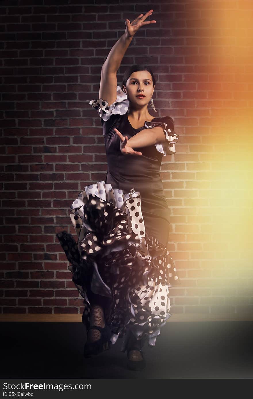 Young girl dancing flamenco. Red brick wall background. Young girl dancing flamenco. Red brick wall background.