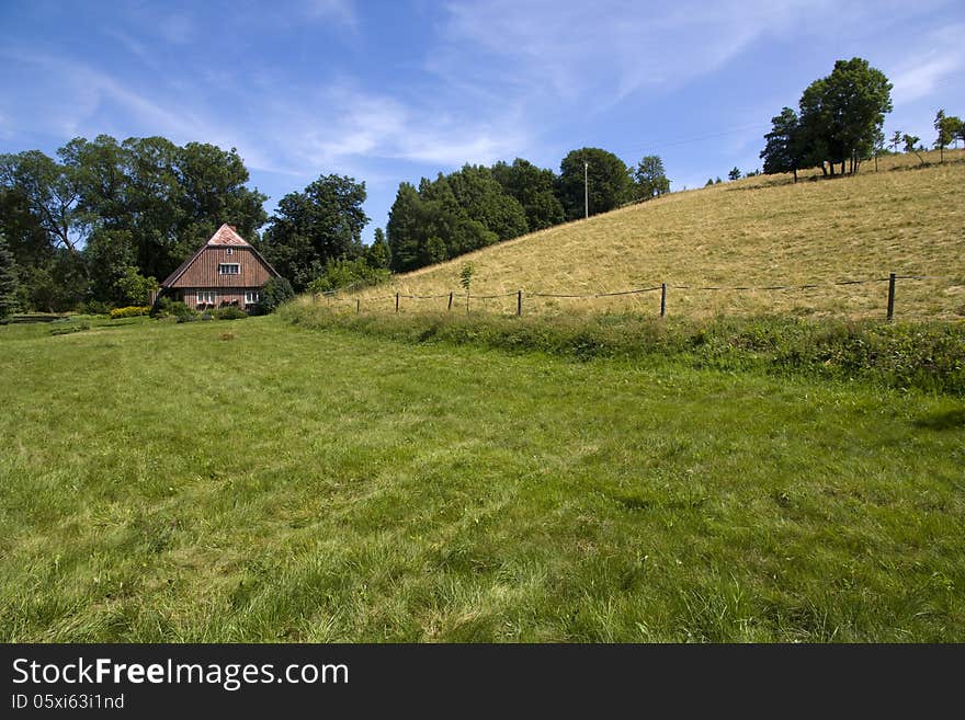 Brown wooden cottage in a green field