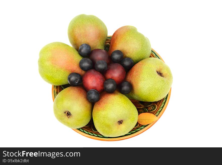 Large ripe pears, plums on a ceramic plate. Presented on a white background. Large ripe pears, plums on a ceramic plate. Presented on a white background.