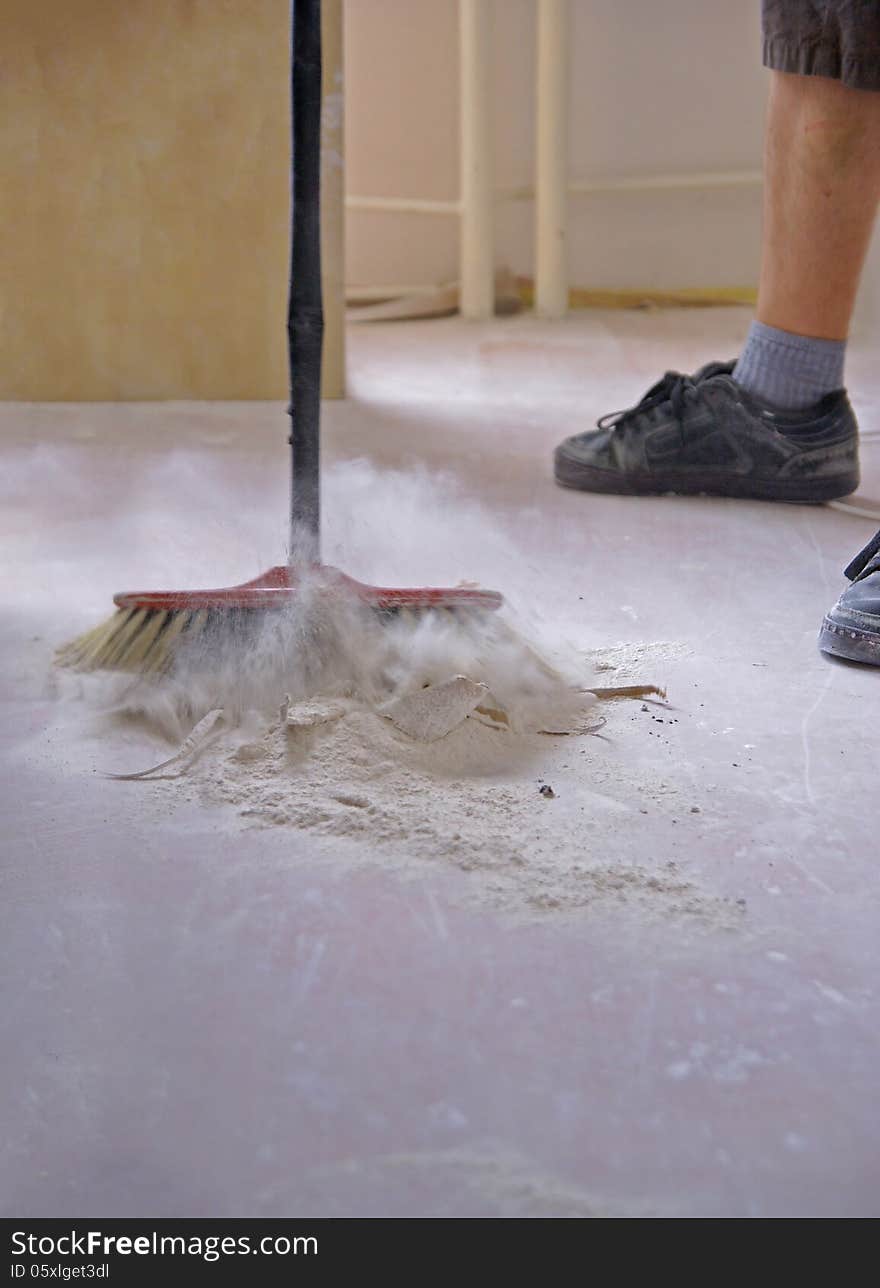 A man sweeps the floor with a broom. A man sweeps the floor with a broom