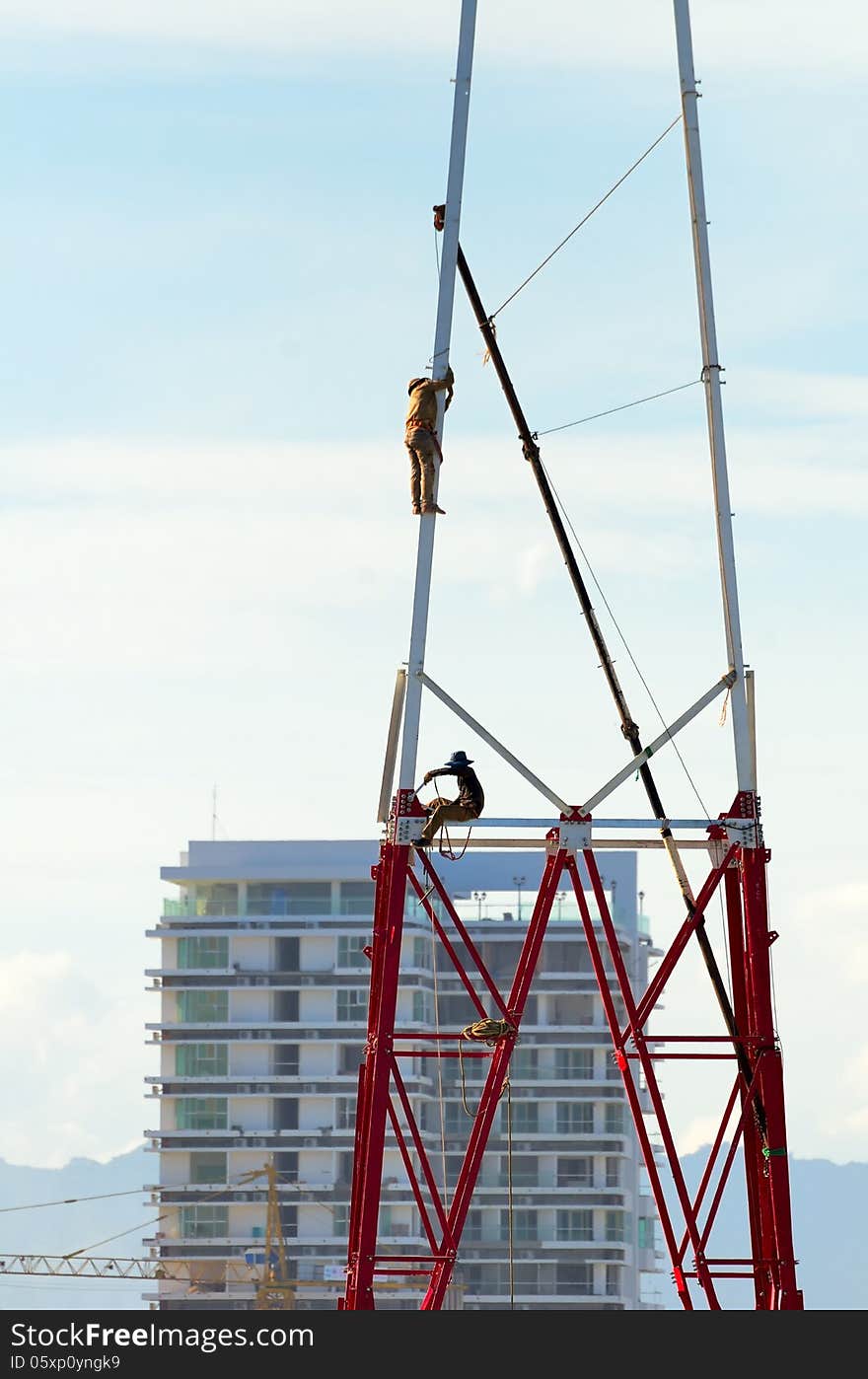 Two workers install a lot of Metal tiered tower on a background of mountains. Two workers install a lot of Metal tiered tower on a background of mountains.