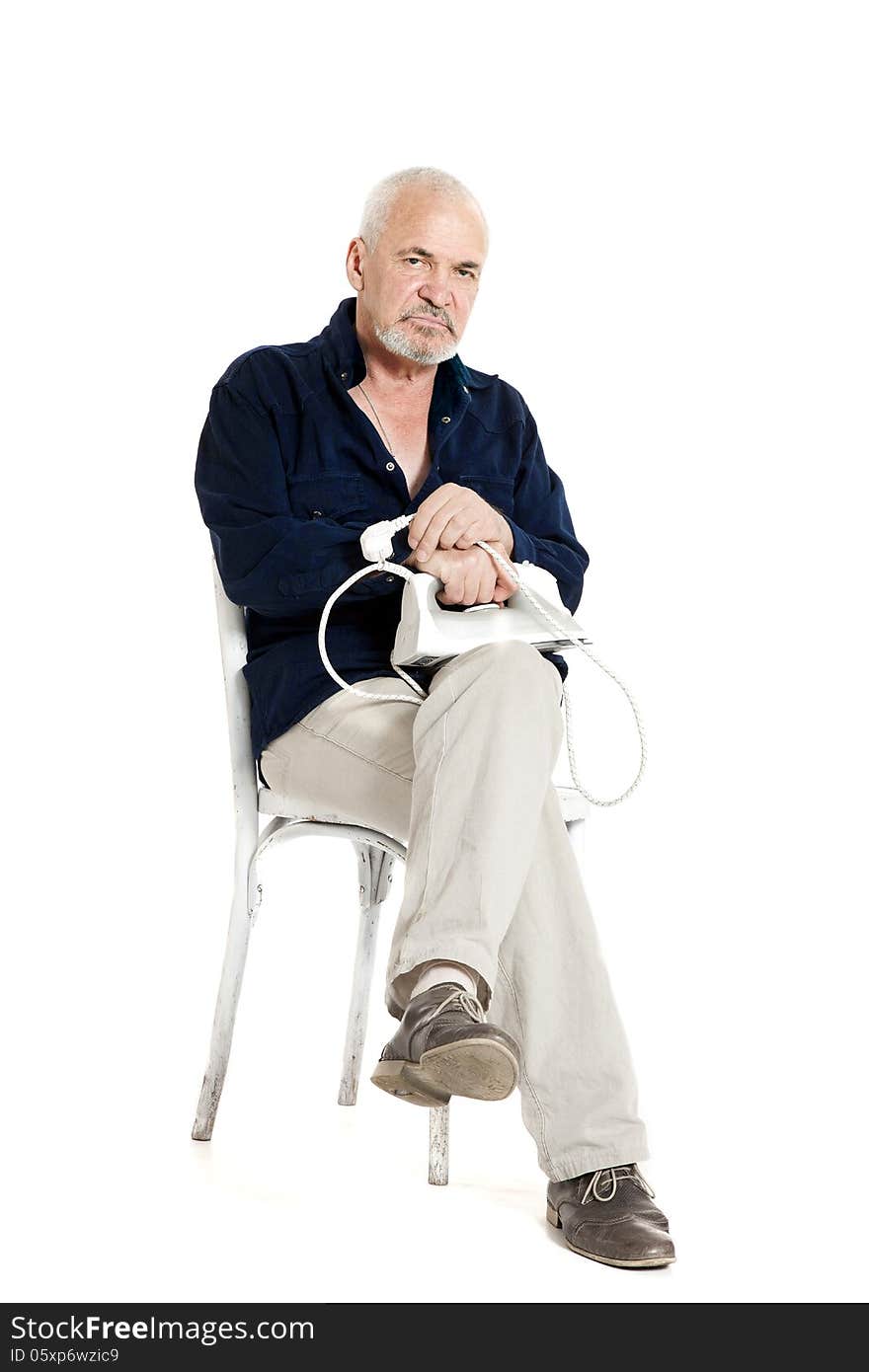 Gray-haired man sitting on a chair and holding electric iron on white background