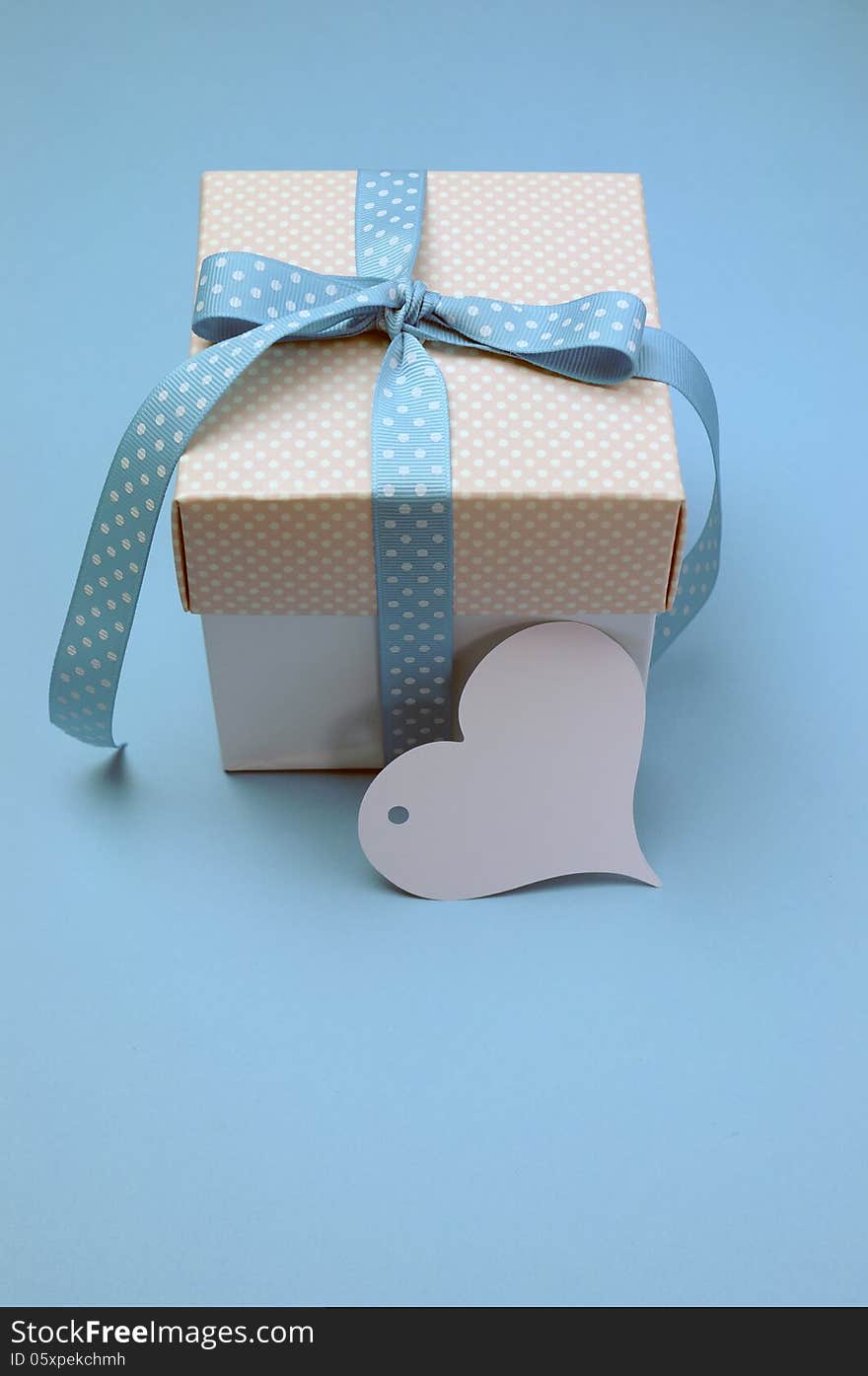 Blue and pink polka dot present with heart shape gift tag on aqua blue background for Christmas, Easter, Fathers Day or birthday present gift giving, with copy space for your text here. Blue and pink polka dot present with heart shape gift tag on aqua blue background for Christmas, Easter, Fathers Day or birthday present gift giving, with copy space for your text here.