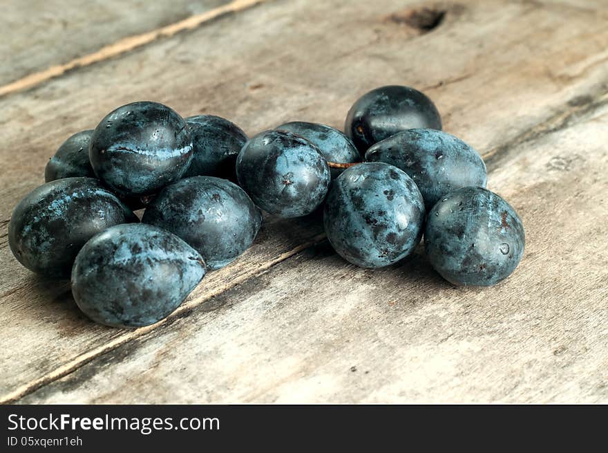 Ripe plums on old wooden table, close up