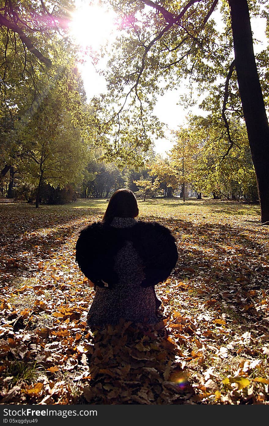 Young woman sitting under the autumn leaves alone. Young woman sitting under the autumn leaves alone