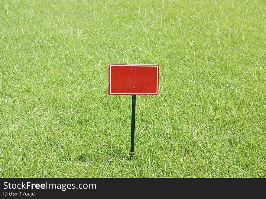 Red metal blank billboard stabbed in greensward. Red metal blank billboard stabbed in greensward